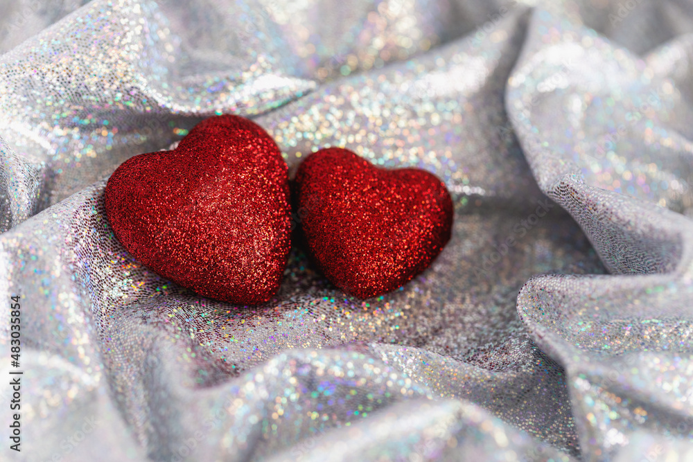 Sparkling red hearts on shiny rainbow fabric. Soft focus.