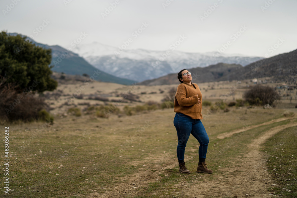 Chica guapa bajita con pelo moreno y gafas paseando por camino de tierra con la sierra nevada de fondo Chica guapa bajita con pelo moreno y gafas paseando por camino de tierra con la sierra nevada de fondo