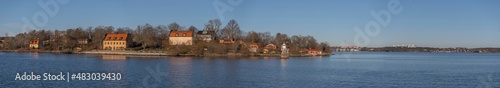 Panorama view of the ness Blockhusudden, color full 1700s houses, and the skyline of the district island Lidingö a sunny winter day in the archipelago of Stockholm
