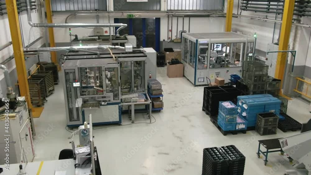 An industrial hall of a plastic molding facility. The machines are working and there are some workers walking around. An industrial hall of a plastic molding facility. The machines are working and there are some workers walking around.