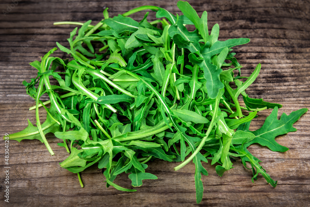 heap of green arugula on wooden background heap of green arugula on wooden background