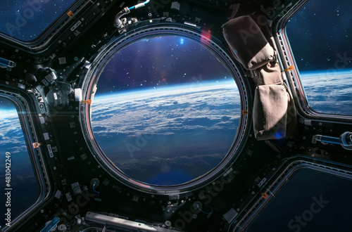Earth planet in ISS porthole. View from Cupola. International space station. Orbit and atmosphere. Elements of this image furnished by NASA photo