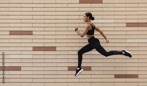 Sport Motivation. Athletic Young Woman In Sportswear Running Over Brick Wall Background