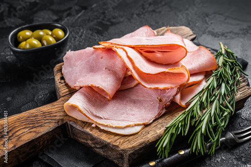 Pork ham slices on cutting board, Italian Prosciutto cotto. Black background. Top view photo