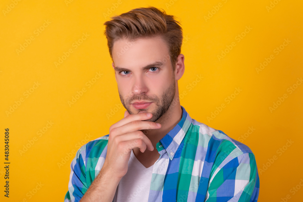 Handsome unshaven guy portrait stroking chin with serious look yellow background, face Handsome unshaven guy portrait stroking chin with serious look yellow background, face