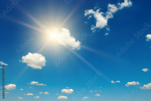 Blue sky with white fluffy clouds and bright sun