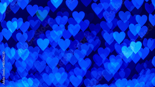 Bokeh background with blue hearts on black background. Love concept. Theme for Valentine's Day