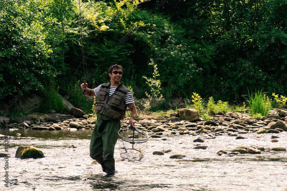 Fototapeta premium Young man fishing trouts in the river
