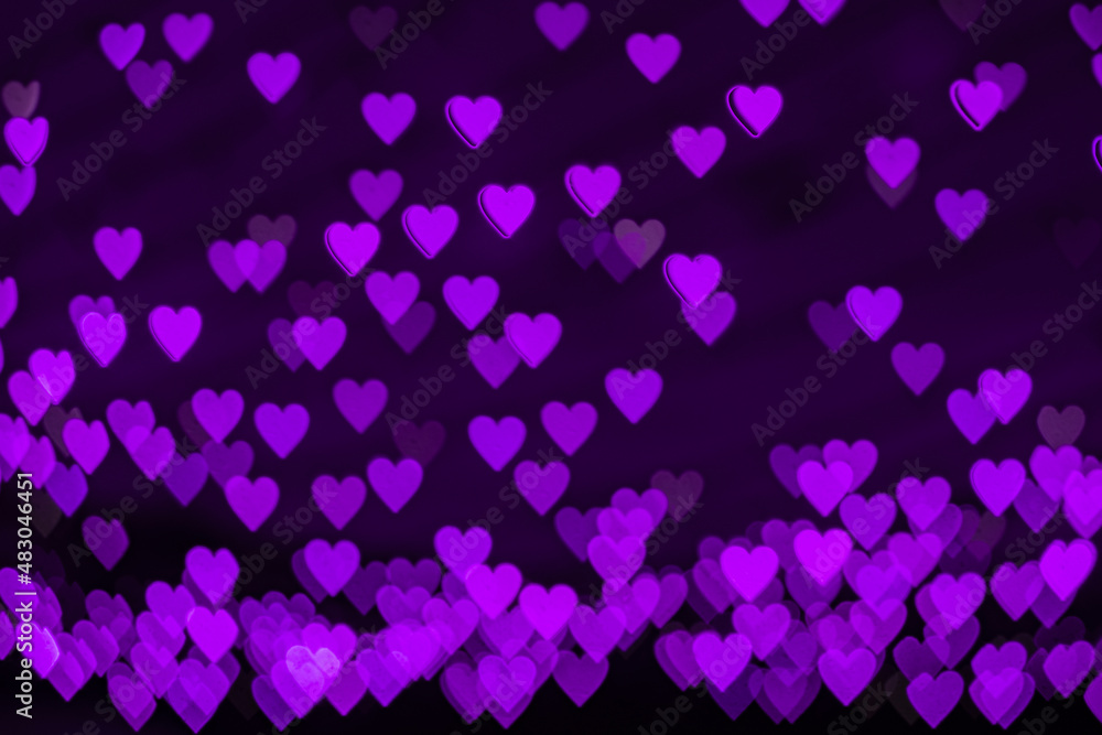 Obraz premium Bokeh background with purple hearts on black background. Love concept. Theme for Valentine's Day
