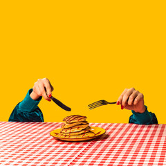 Food pop art photography. Female hand and sweet pancakes on plaid tablecloth isolated on bright yellow background. Vintage, retro style