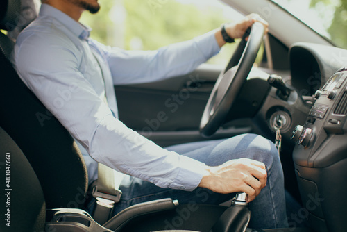 Unrecognizable businessman driving comfy auto, holding hand on gear