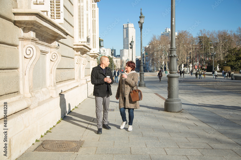 senior Caucasian couple strolling with a paper cup with coffee senior Caucasian couple strolling with a paper cup with coffee