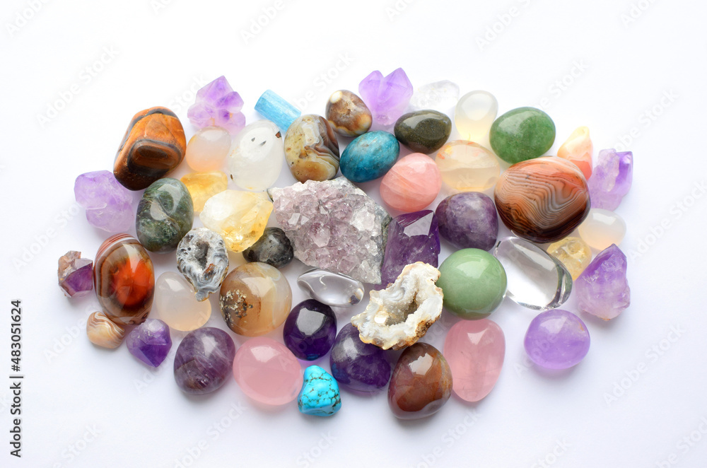 Gems of different colors. Amethyst, rose quartz, agate, apatite, aventurine, olivine, turquoise, aquamarine, rhinestone lie on a white background. Top view Gems of different colors. Amethyst, rose quartz, agate, apatite, aventurine, olivine, turquoise, aquamarine, rhinestone lie on a white background. Top view