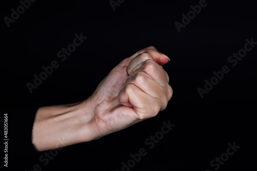 Clenched fist of Caucasian person on black background. Domestic physical and psychological abuse, relative aggression, gaslighting and social injustices. Copy space.