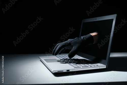 internet fraud and cyber attack concept. thief hand out of laptop screen photo