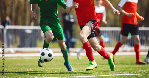 Fototapeta Naklejka Na Ścianę i Meble -  Football men running ball in a duel. Adult soccer players in competition game. Athletes kicking soccer ball on grass pitch