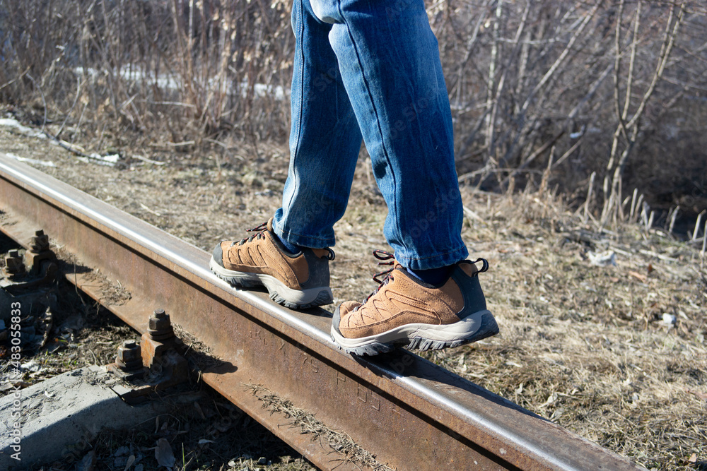 legs of a person walking on railway tracks legs of a person walking on railway tracks