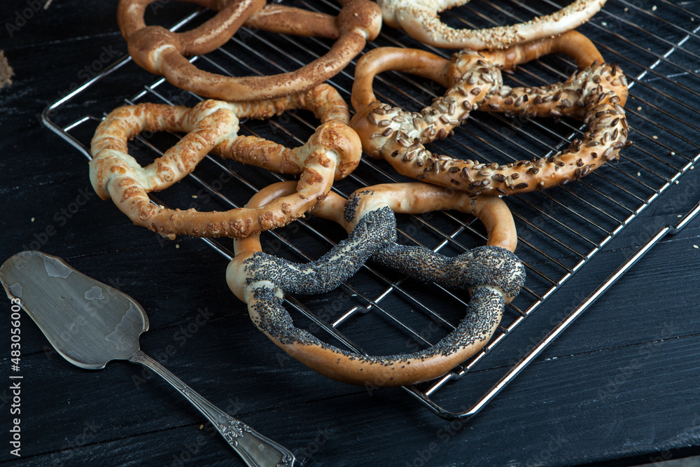 Fototapeta premium Fresh prepared homemade soft pretzels. Different types of baked bagels with seeds on a black background.