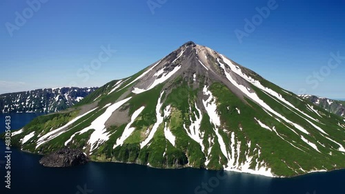 Glorious aerial panorama. Green and white volcano cone, blue water around, sunny