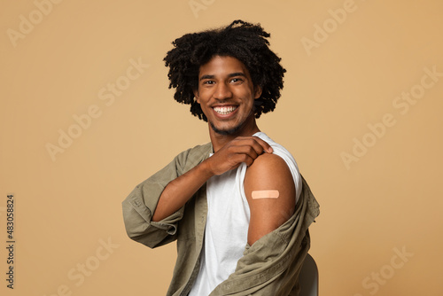 Vaccination Concept. Black Guy Demonstrating Arm With Adhesive Bandage After Covid-19 Vaccine