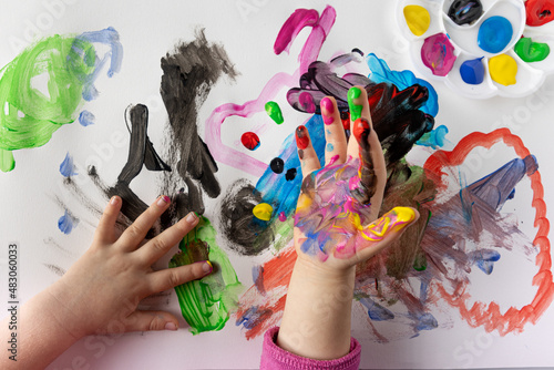 Girl at school painting with finger paints. Lots of colors and lots of fun. Girl's hands stained with paint. photo