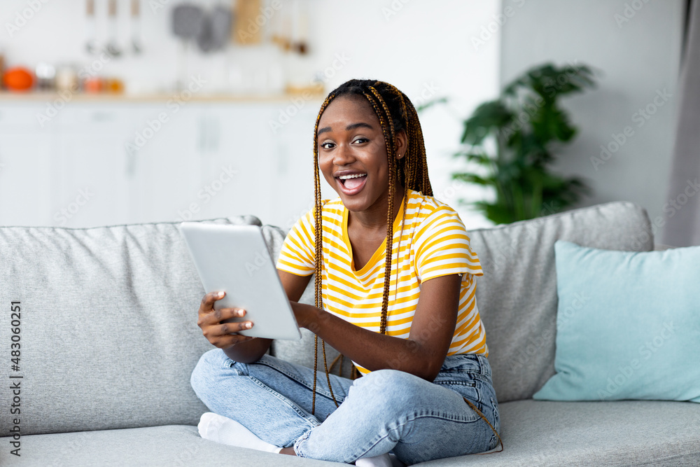 Obraz premium Smiling black woman trader working on pad from home