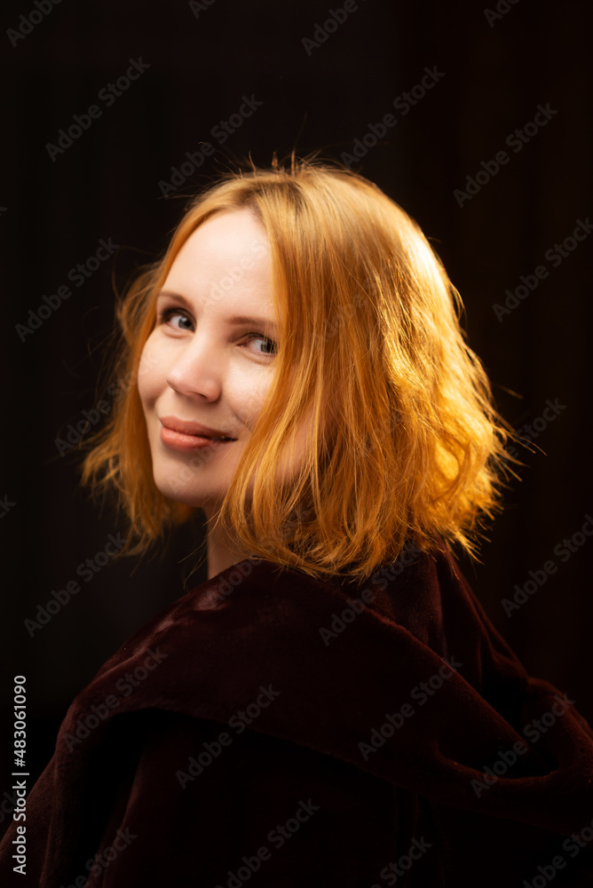 Portrait of an attractive red-haired woman against a dark background. A middle-aged woman, forty years old. Happy face. Portrait of an attractive red-haired woman against a dark background. A middle-aged woman, forty years old. Happy face.