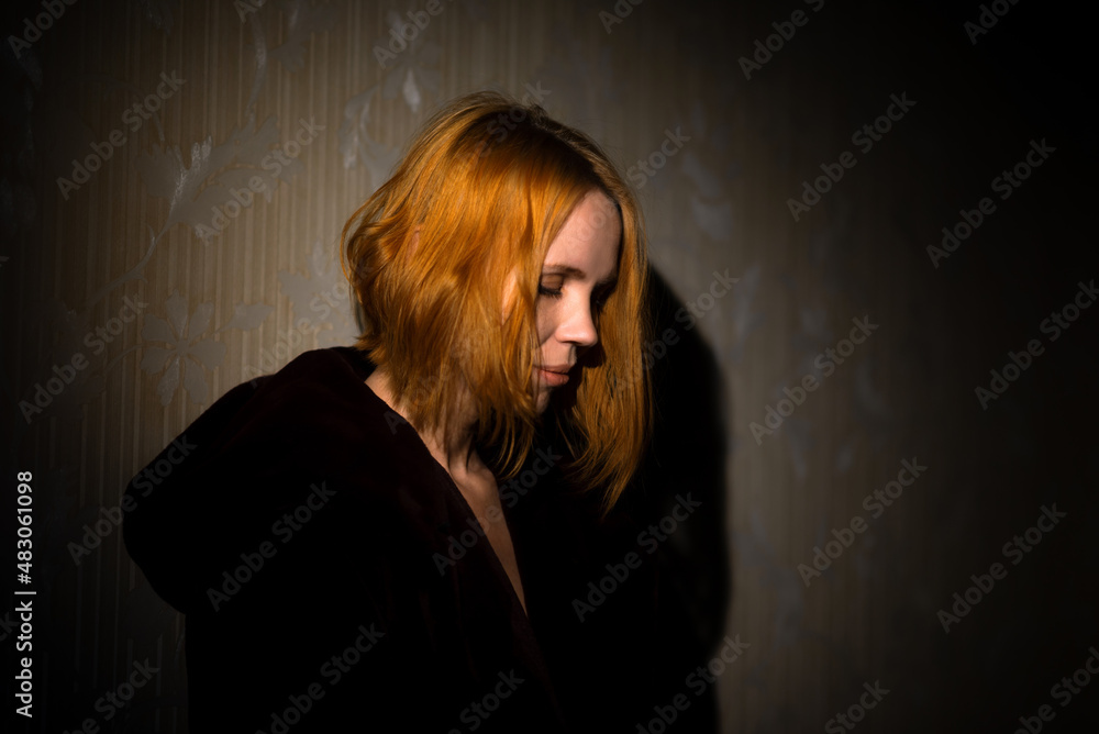 Fototapeta premium Middle aged woman dramatic portrait. A woman of forty years old, illuminated by a beam of light. Meditation, midlife crisis concept.