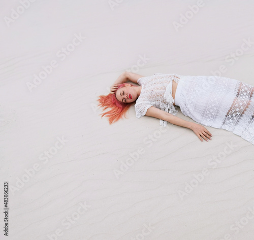 young beautiful woman with pink hair in a white wedding dress in boho style on the background of a sandy beach. Honeymoon, custom wedding. freedom, love, sunny day, white sand, summer holidays,day off