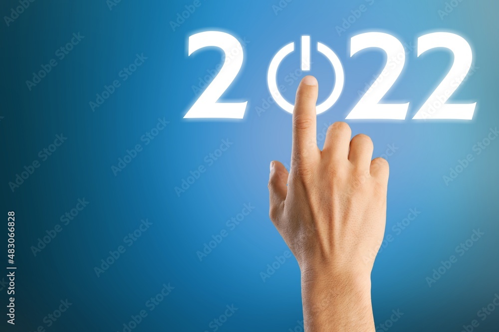 hand presses the start button for 2022. Happy New Year resolution, change, goal, vision, hand presses the start button for 2022. Happy New Year resolution, change, goal, vision,