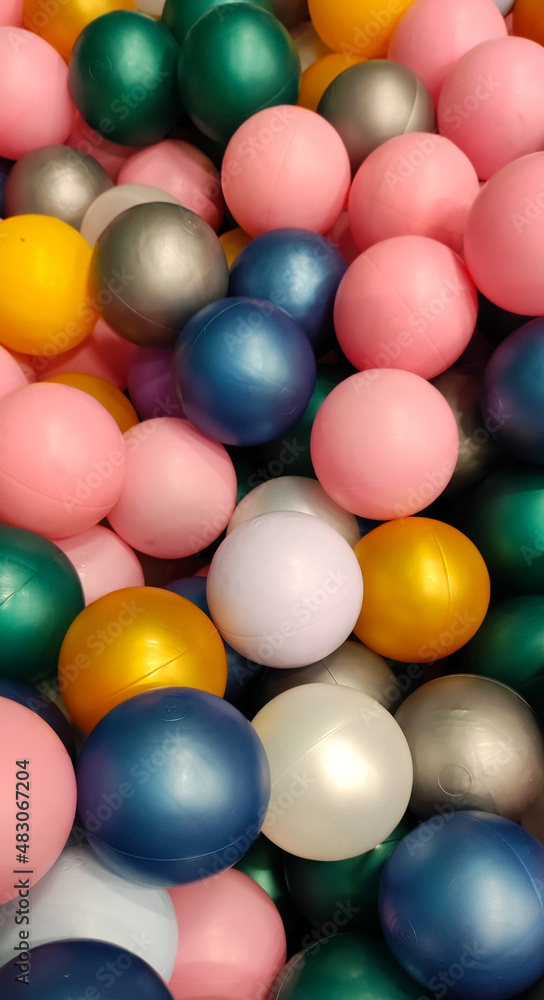 Fototapeta premium bright festive multi colored small plastic balls are scattered with a colored background