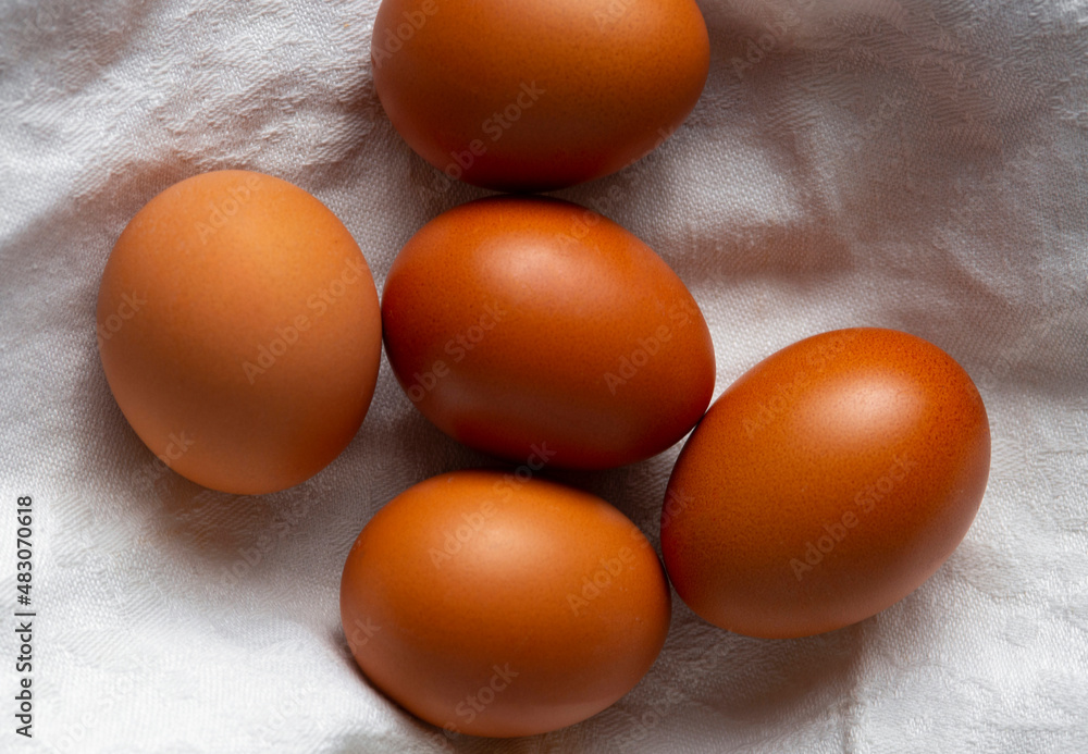 Brown eggs on a white towel and wicker basket. Top view, flat lay Brown eggs on a white towel and wicker basket. Top view, flat lay