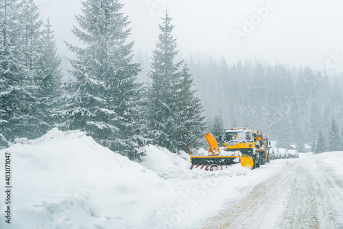 Snow plough on snowy mountain road during winter blizzard
