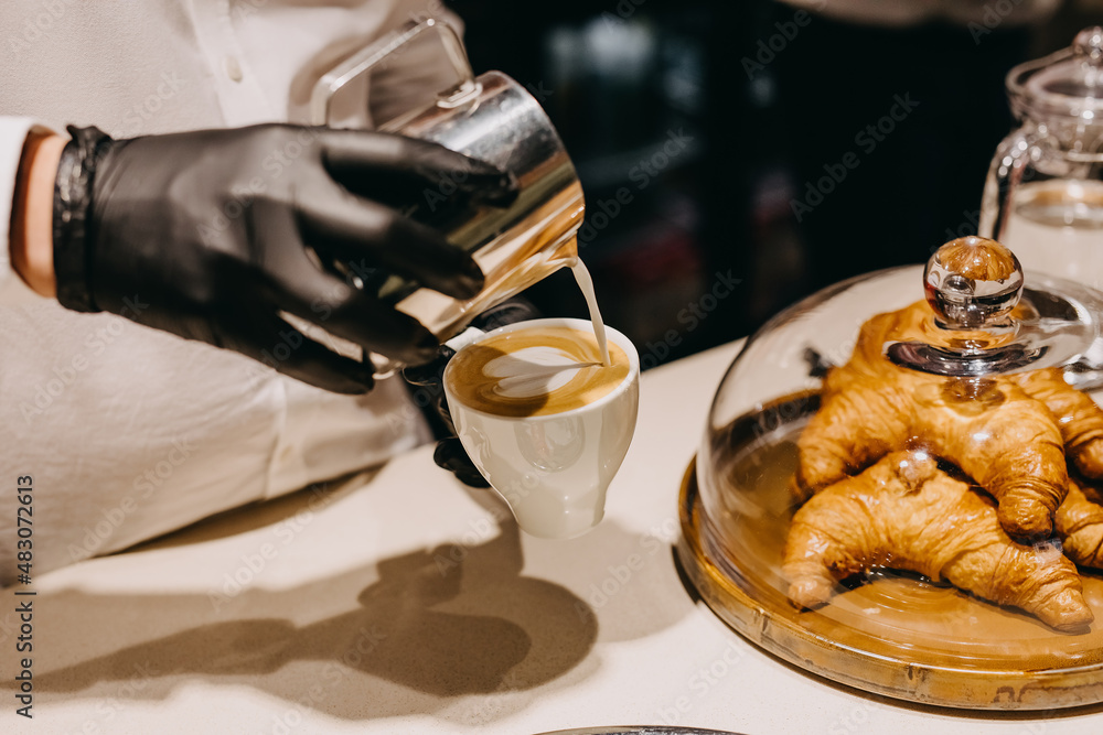 Barman drawing a heart on cappuccino foam, in a white cup. Barman drawing a heart on cappuccino foam, in a white cup.