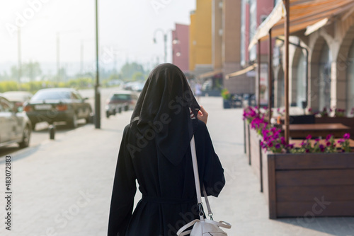 A single Muslim woman walks through empty big city rear view. © ALEXEY