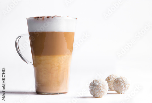 Latte macchiato in a tall glass on a white background. Cafe latte layered with milk in a high drinking glass. Minimalism. Сopy space photo