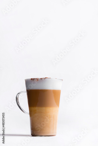 Latte macchiato in a tall glass on a white background. Cafe latte layered with milk in a high drinking glass. Minimalism. Сopy space