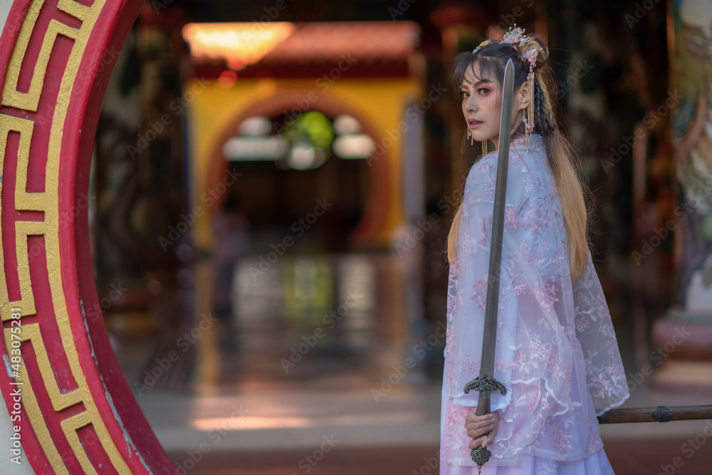 Asian woman wearing traditional Chinese dress pink white color holding Chinese sword