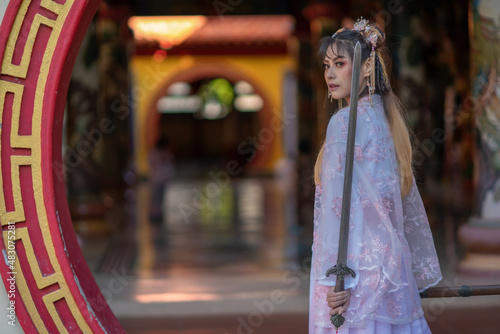Asian woman wearing traditional Chinese dress pink white color holding Chinese sword
