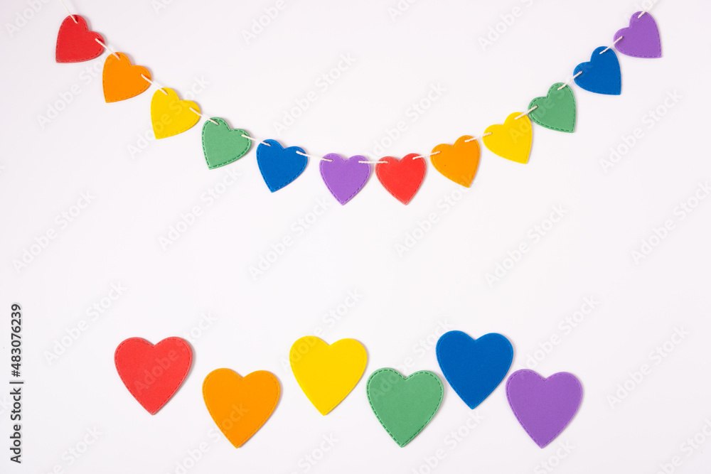 Colorful garland handmade hearts in colors of LGBT on the white textured background.