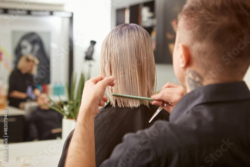 Hairdresser combing woman hair in beauty salon