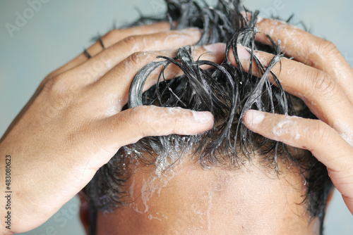 young men washes h his hair with shampoo .