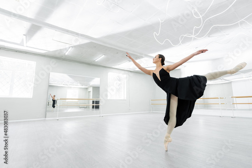 full length view of ballerina dancing in spacious studio during repetition
