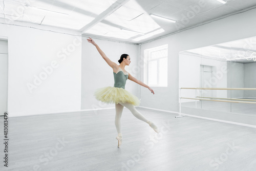 full length view of graceful ballerina dancing in spacious ballet studio