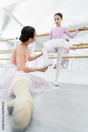 ballet teacher assisting girl during training in dance studio