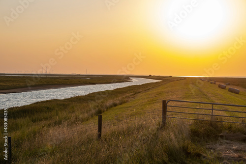 View over the dyke towards the setting sun over the Langwarder Groden Germany on the North Sea 