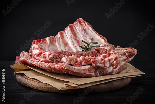 Fotografie, Obraz Raw pork ribs on a wooden board on a dark background