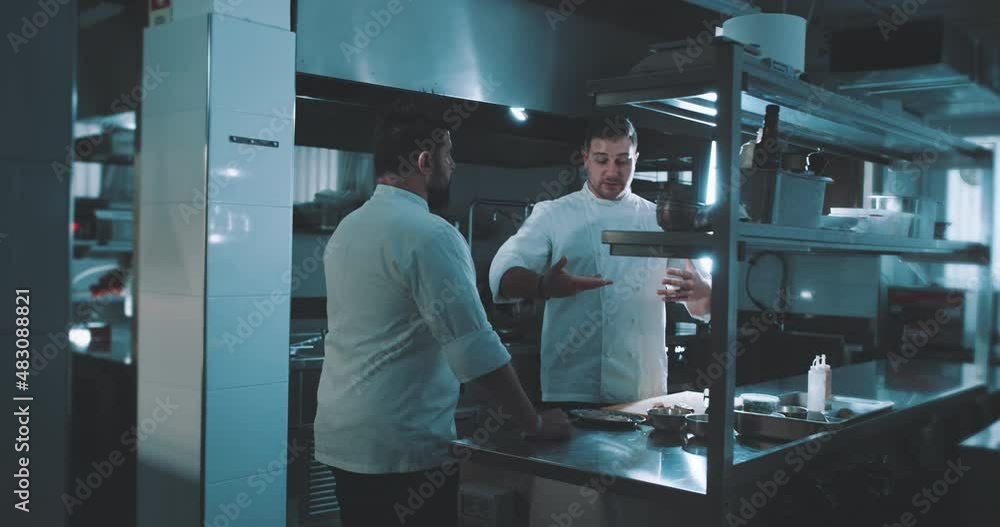 Two chefs have a conversation in kitchen Two chefs have a conversation in kitchen
