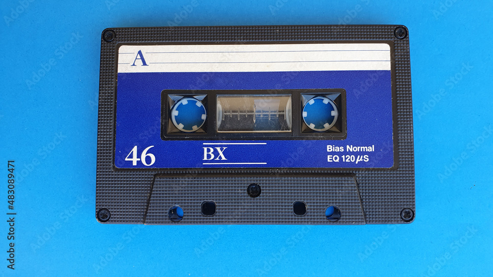 Retro audio cassette tapes on blue background. Vintage media device. Space to write on the label.