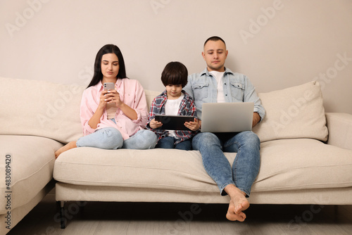 Happy family with gadgets on sofa at home